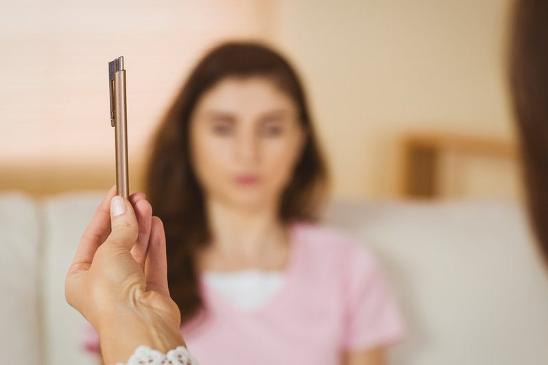 Traumatherapie / Mind Balance Eine Person hält einen Stift, während eine andere Person im Hintergrund sitzt.